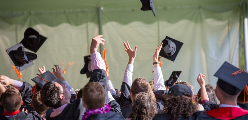 College grads throwing their caps up into the air at a graduation ceremony.