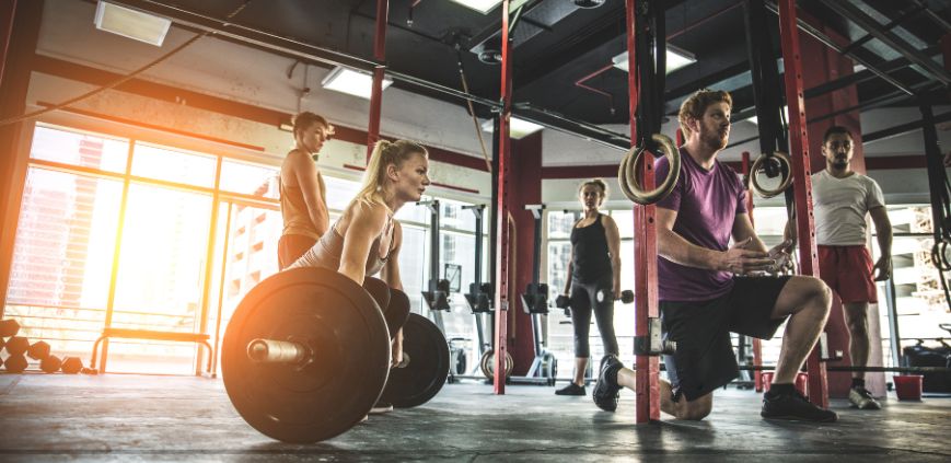 A group of people lifting weights and working out in a gym setting.