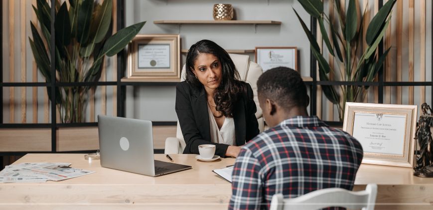 A female lawyer sitting at a desk talking to a male client.