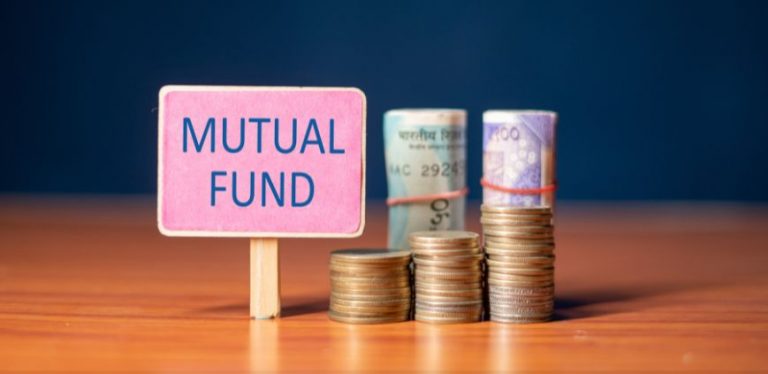 A pink sign that says "mutual fund" in front of coins and paper money, sitting on a table.