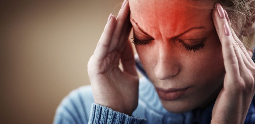 A woman holding her head as if experiencing a headache. There is red over her forehead to represent pain.